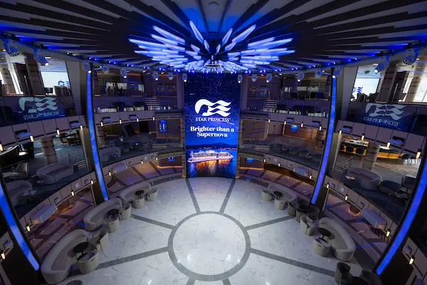 The Piazza inside the Star Princess cruise ship with a multi-level atrium, blue lighting, and lounge seating.