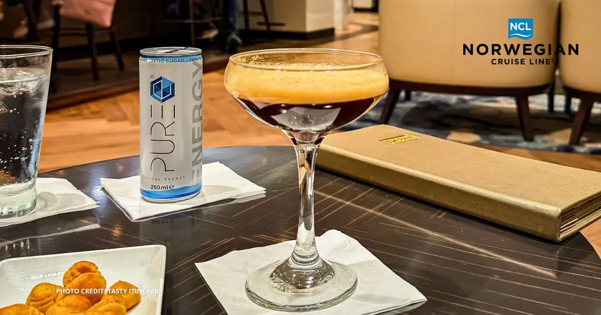 featured image: A freshly shaken espresso martini sits on a lounge table aboard a Norwegian Cruise Line ship, with a can of energy drink and snacks nearby. Overlay text reads: NCL Brings Back Free at Sea.