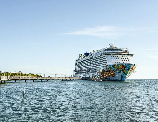 The Norwegian Getaway cruise ship docked at Harvest Caye, Belize, with the long pier connecting Norwegian Cruise Line’s private island to the ship.