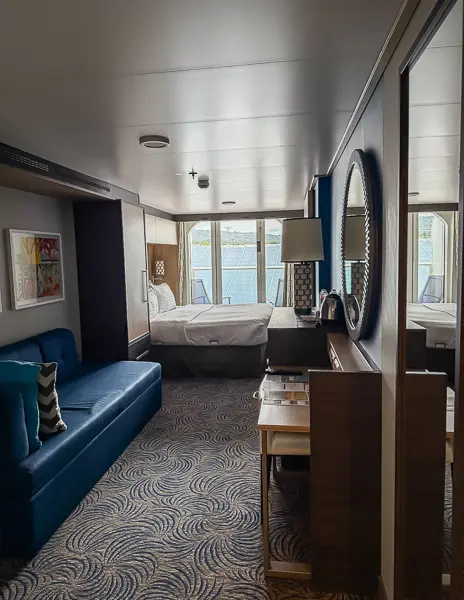Full view of balcony cabin 6560 on Quantum of the Seas, showing the sofa, vanity, bed, and floor-to-ceiling balcony doors.