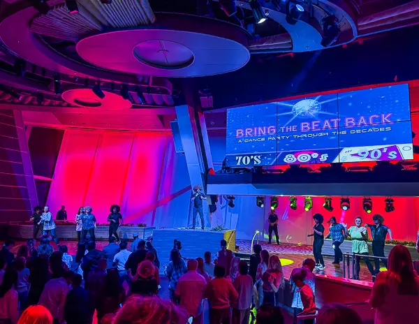 Bring Back the Beat dance party in Two70 on Quantum of the Seas, with performers onstage and guests dancing under vibrant lighting.