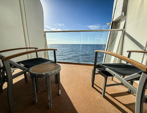 Balcony of cabin 6560 on Quantum of the Seas, with two chairs, a small table, and an ocean view on a sunny day.