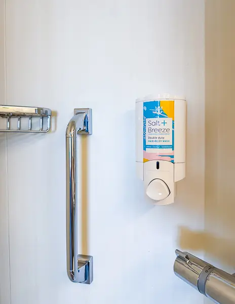 Close-up of the shampoo and body wash dispenser inside the shower of balcony cabin 6560 on Quantum of the Seas.