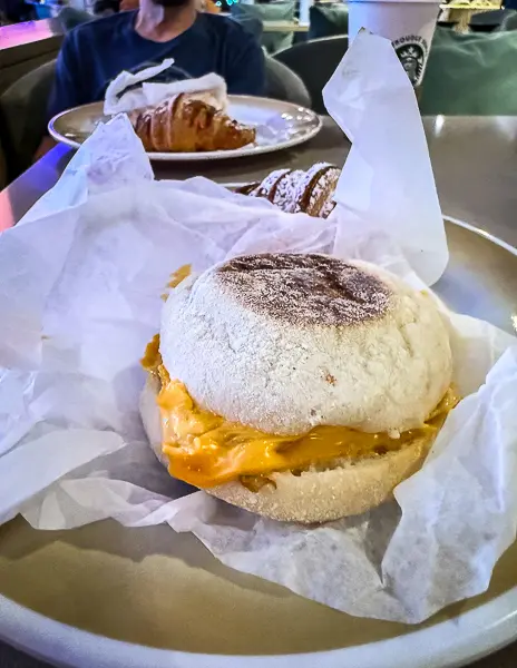 Breakfast sandwich served at Café Two70 on Quantum of the Seas, shown on a plate with cheese melting over the untoasted English muffin.