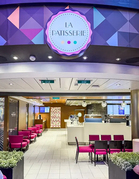 Entrance to La Patisserie on Quantum of the Seas, featuring bright pink seating, a modern geometric sign, and a dessert and specialty coffee counter inside.
