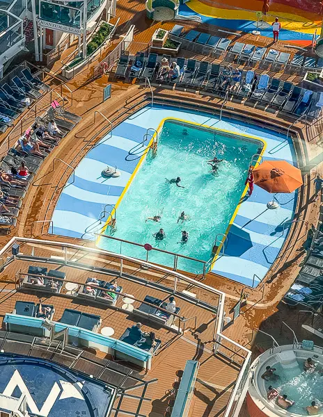 Top-down view of the main pool on Quantum of the Seas, with guests swimming and lounging around the deck.