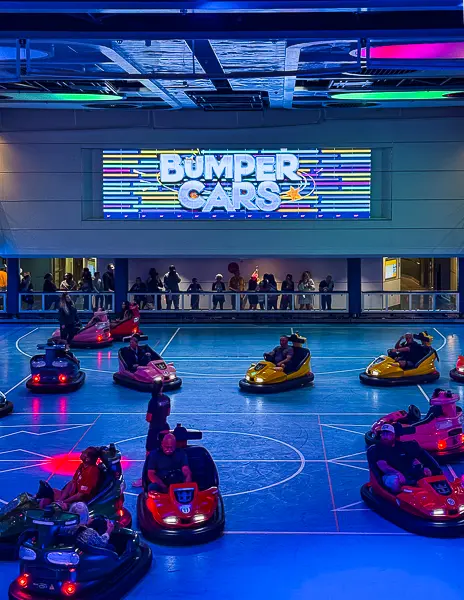 Bumper cars in action inside the SeaPlex on Quantum of the Seas, with colorful lights and spectators watching from the balcony.