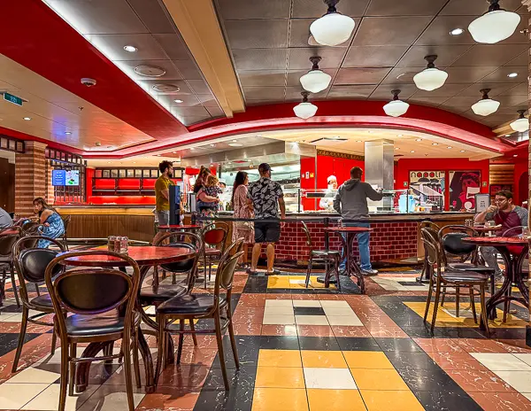 Inside Sorrento’s on Royal Caribbean’s Quantum of the Seas, showing guests waiting at the pizza counter and tables throughout the venue.