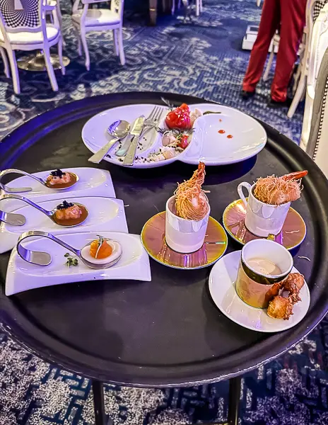 Selection of Wonderland appetizers on Quantum of the Seas, served on a tray with small bites arranged on decorative plates and spoons.