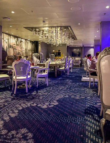 Inside the Wonderland restaurant on Quantum of the Seas, featuring whimsical chairs, chandeliers, and dramatic themed décor.