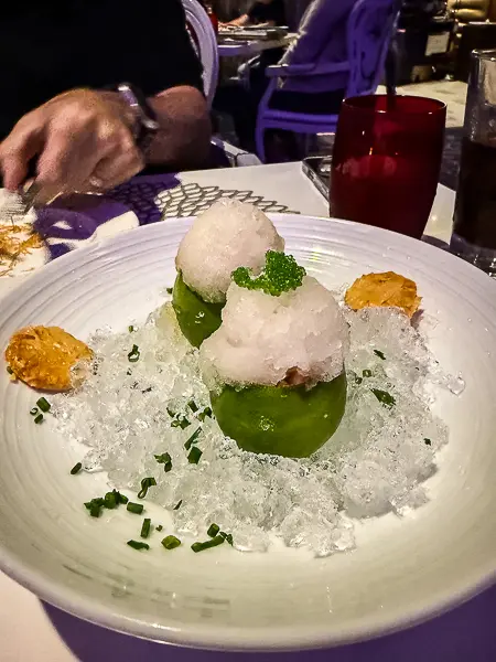 Spicy tuna served inside hollowed limes on a bed of crushed ice at Wonderland on Quantum of the Seas, topped with granita and small garnishes.