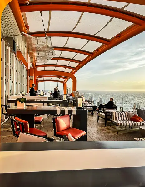 Cruise ship outdoor lounge, the magic carpet on Celebrity Beyond, with ocean views on a sea day, showing guests enjoying the ship between ports.
