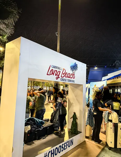 Photo spot inside Carnival’s Long Beach Cruise Terminal, with passengers walking through the dome near a Long Beach Cruise Terminal display.