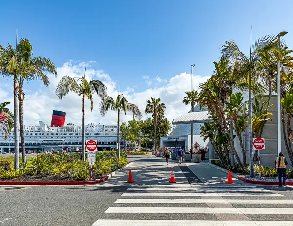 Walkway near the Long Beach Cruise Terminal with palm trees and the Queen Mary visible in the background.