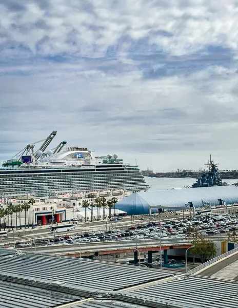 View of the San Pedro World Cruise Center with a cruise ship docked, the terminal buildings, and parking areas visible from above.