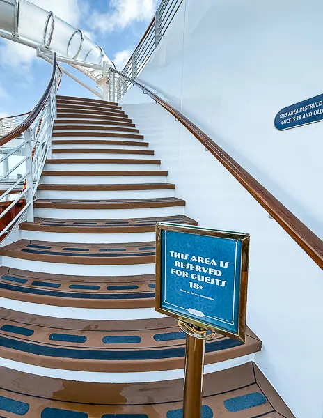 Staircase on a Disney cruise ship marked as reserved for guests 18 and older leading to an adults-only area.