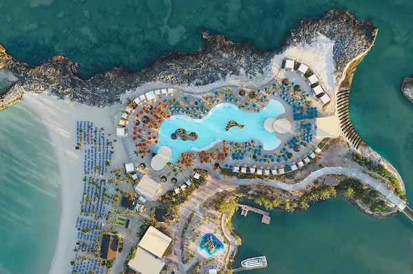 Aerial promotional image from Norwegian Cruise Line showing the planned Great Life Lagoon pool area at Great Stirrup Cay, with surrounding loungers, cabanas, walkways, and nearby beach areas.