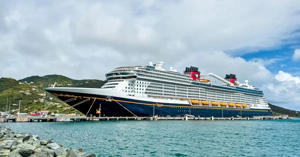 featured image: Disney Treasure docked in Tortola port with turquoise water and green hills in the background, featured image for our Disney Treasure review.