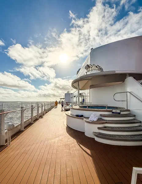 Quiet Cove adults-only deck on Disney Treasure with hot tub, steps, and ocean views under the sun.