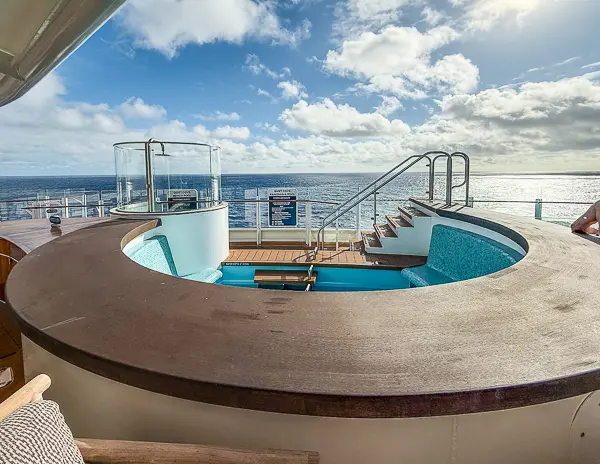 Adults-only Quiet Cove wading pool on Disney Treasure with built-in seating and ocean views.