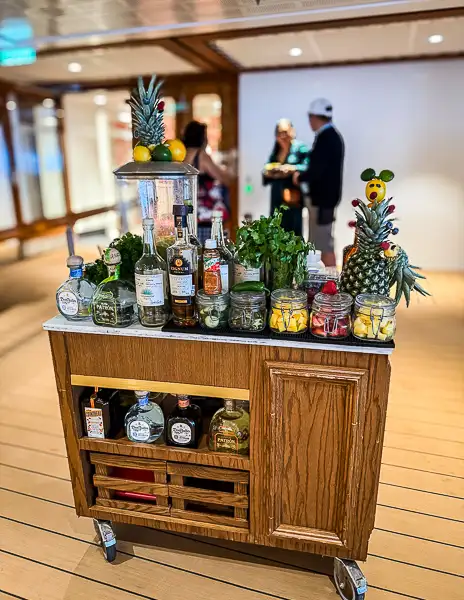 Margarita cart on the pool deck of Disney Treasure with fresh ingredients and liquor bottles displayed.with fresh ingredients and liquor bottles displayed.