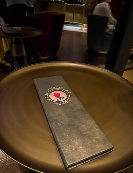 The Rose cocktail menu resting on a round table inside The Rose lounge on Disney Treasure.