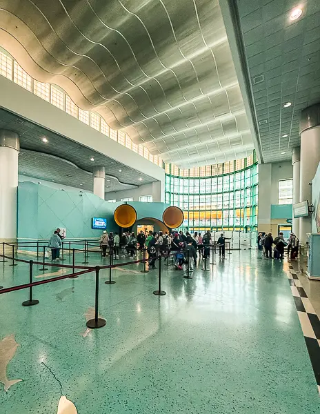Inside the Disney Cruise Line terminal at Port Canaveral with guests lined up for embarkation near the Mickey-shaped entrance.