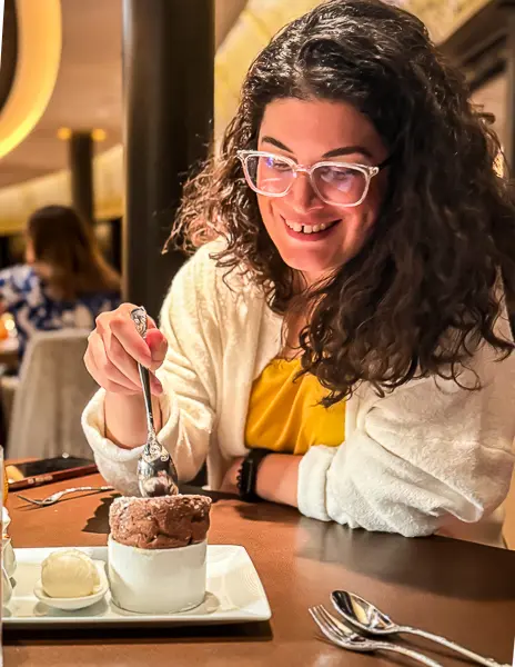 Kathy enjoying chocolate soufflé dessert at Palo Steakhouse on Disney Treasure.