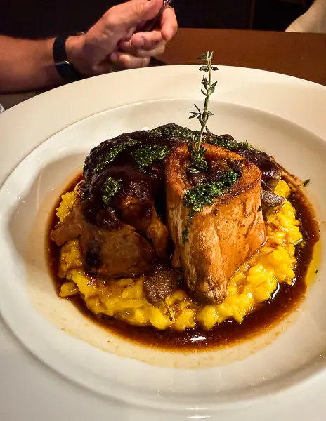 Osso buco served at Palo Steakhouse on Disney Treasure over saffron risotto with rich sauce and fresh herbs.