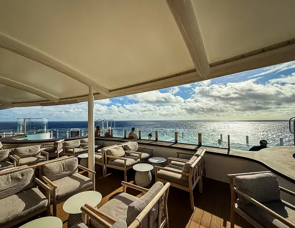 Quiet Cove adults-only pool deck on Disney Treasure with lounge seating and ocean views at the aft of the ship.