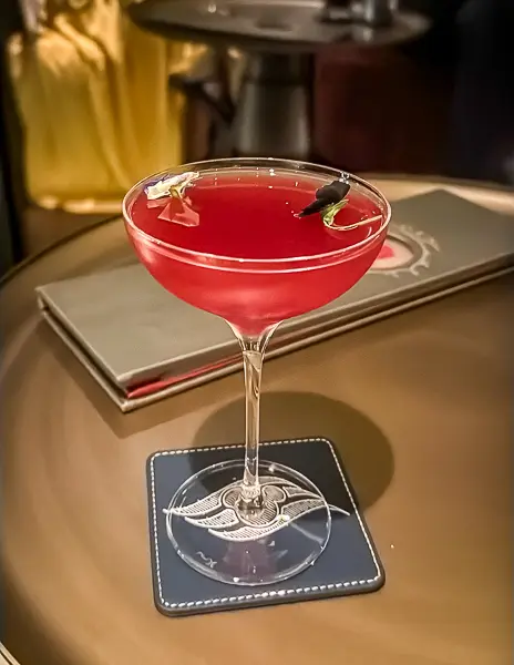 Plant & Fleurs cocktail served at The Rose lounge on Disney Treasure in a coupe glass.