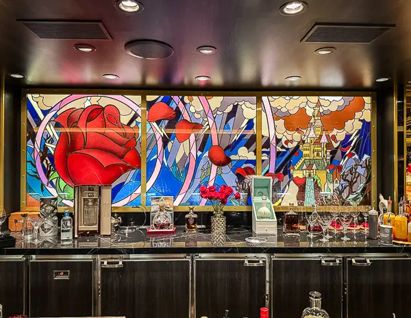 Beauty and the Beast stained glass mural behind the bar inside The Rose lounge on Disney Treasure.