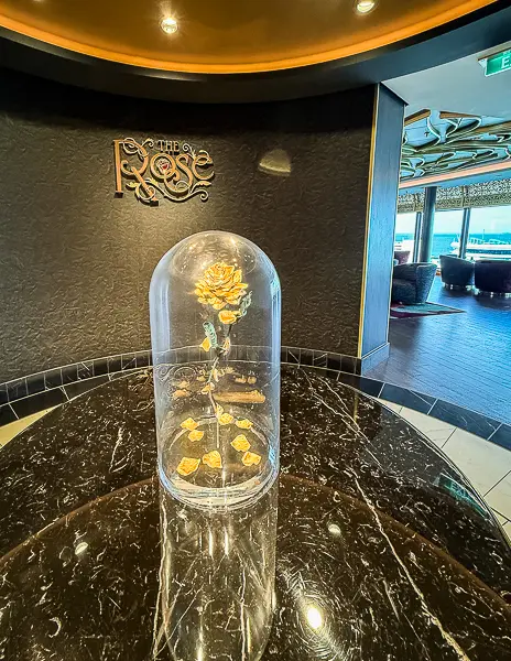 The Rose lounge entrance on Disney Treasure featuring the enchanted rose under a glass dome on a marble table.