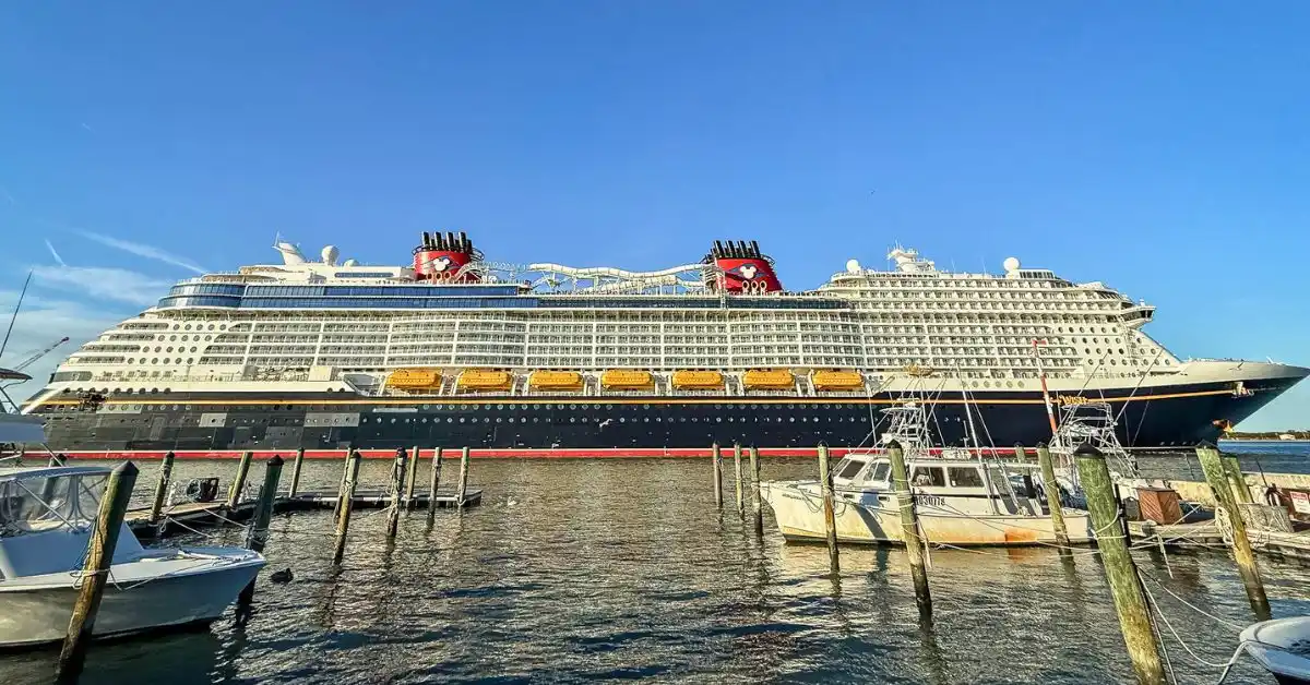 Disney Cruise Line ship docked at port with red Mickey funnels and lifeboats visible, representing things Disney Cruise Line does that other cruises don’t.