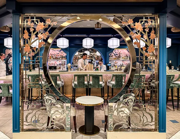 Disney Treasure’s Jade Cricket Café and Bar with decorative circular entrance, floral details, and bar seating inside the themed lounge on Disney Cruise Line.