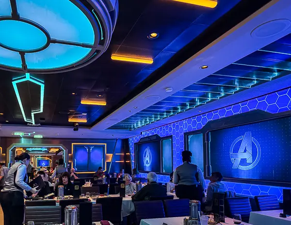 Marvel-themed restaurant onboard a Disney Cruise Line ship with Avengers logos on the walls and guests dining inside the immersive Marvel dining experience.