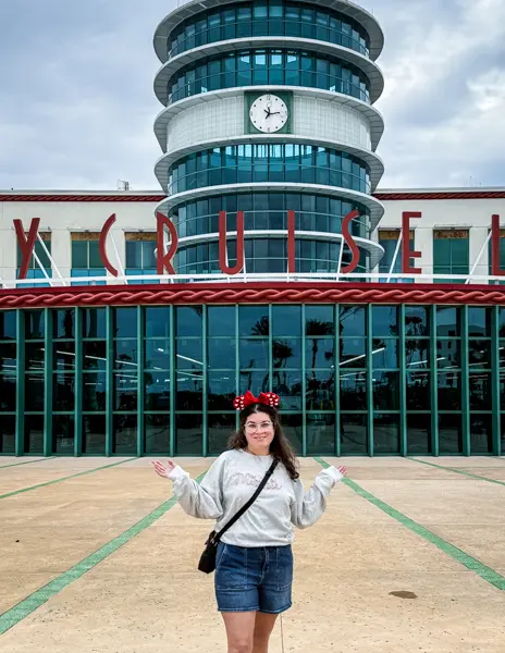Woman (kathy) wearing Minnie ears, grey sweatshirt, and denim shorts on embarkation day at Disney Cruise Line terminal