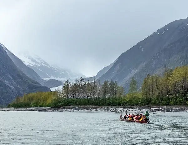 Large canoe on glacier-fed water with Davidson Glacier in the distance during the Glacier Point Wilderness Safari from Skagway.