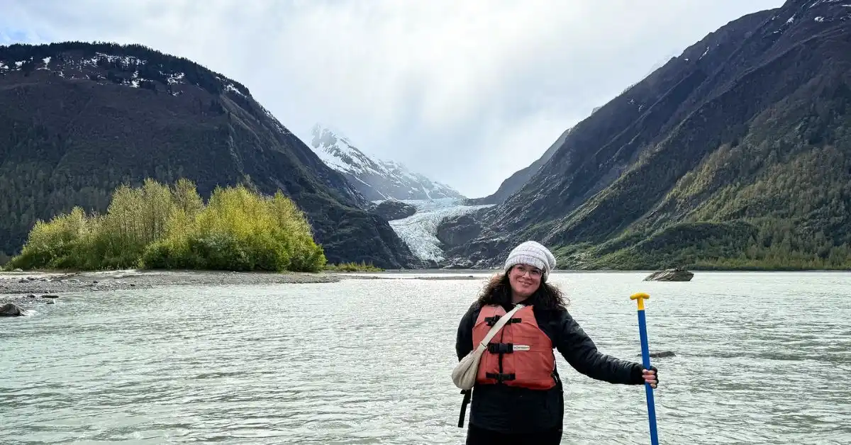 featured image: Kathy wearing a life vest and holding a paddle near Davidson Glacier during the Glacier Point Wilderness Safari from Skagway boat ride and canoeing excursion.