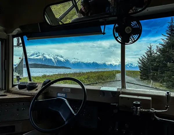 View from inside the old school bus at Glacier Point with snowcapped mountains visible through the windshield.