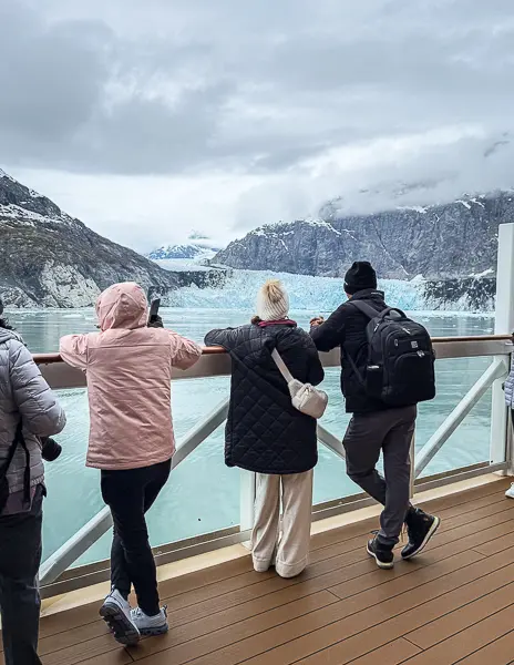Passengers viewing glacier scenery from a cruise ship public deck during an Alaska cruise.