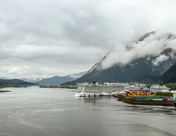 Cruise ships docked at the Juneau cruise port with misty mountains and water in the background during an Alaska cruise.