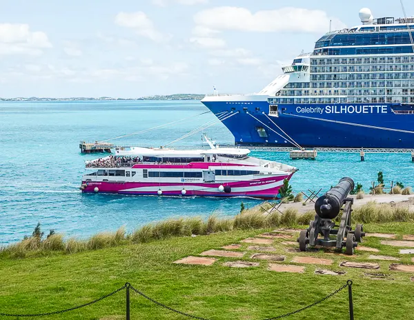 Norwegian Cruise Line ferry returning to the pier at the Bermuda cruise port near Royal Naval Dockyard, with a Celebrity cruise ship in the background.