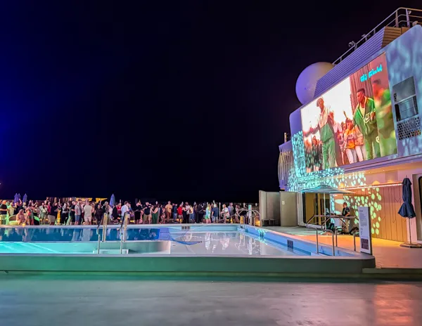 90s pool deck party on Norwegian Aqua with music videos playing on the large screen by the main pool.
