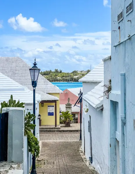 Stepped white roofs and colorful buildings along a narrow street overlooking the water in Bermuda.