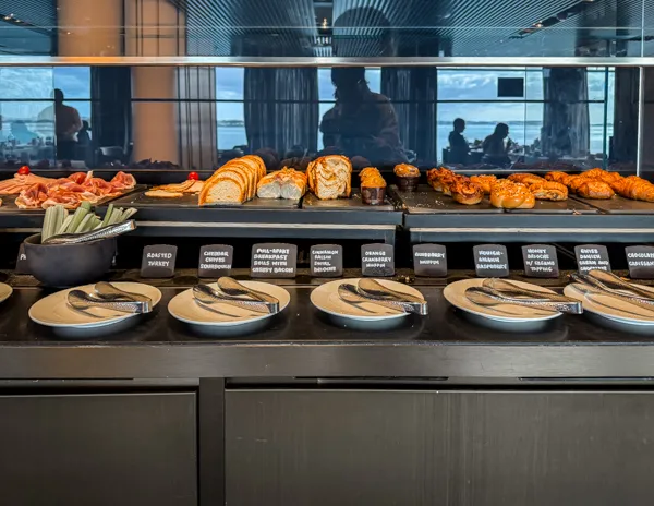 Breakfast buffet spread inside Norwegian Aqua The Haven Restaurant with pastries, meats, and small bites.
