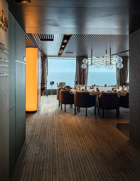 Entrance to Norwegian Aqua The Haven Restaurant with dining tables, ocean views, and modern decor.
