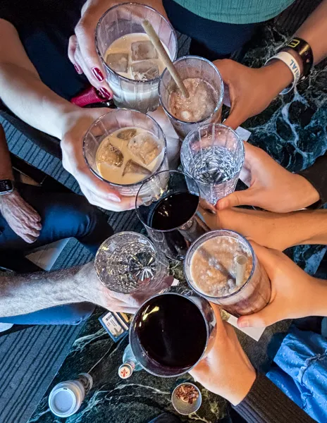 Family toast with cocktails, mocktails, and water inside Norwegian Aqua The Haven Lounge.