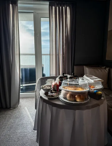Butler-delivered breakfast in Norwegian Aqua The Haven suite with coffee, pastries, fruit, and balcony views.