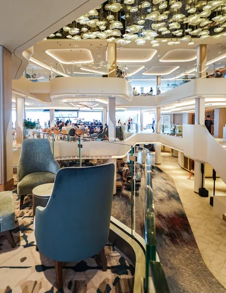 Norwegian Aqua three-deck atrium with lounge seating, glass railings, and open public spaces.